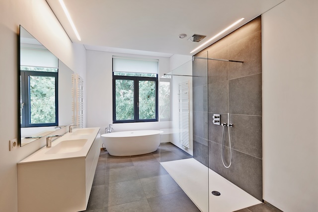 Bathtub in corian, Faucet and shower in tiled bathroom with windows towards garden